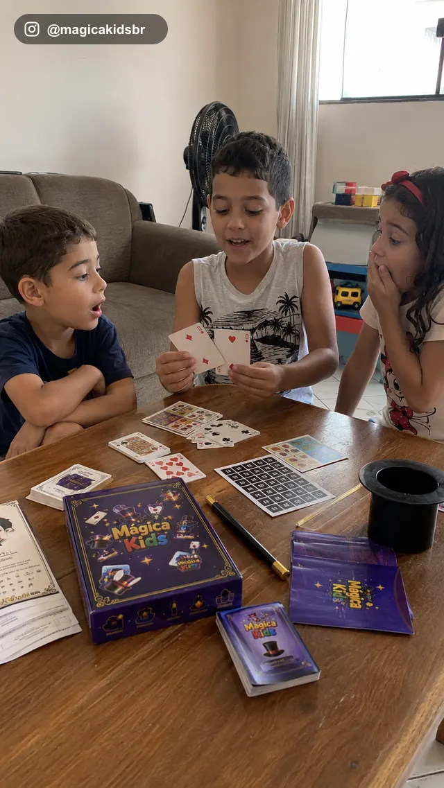 Três crianças reagindo surpresas a um truque de cartas